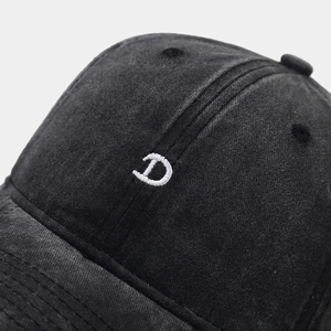 Macro shot of 3D letter D embroidery on washed black cotton vintage baseball cap texture