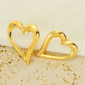 Boucles d'oreilles cœur évidé en or avec un design minimaliste en métal poli sur marbre