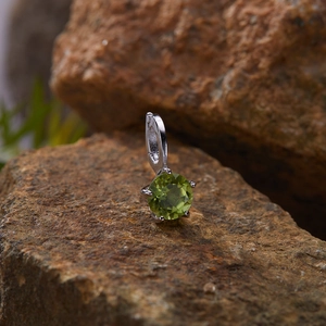 Macro shot of a green gemstone pendant set in S925 silver on a natural brown rock