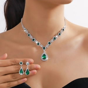 Luxury silver-tone jewelry set with emerald green pear-cut crystals worn by a model