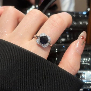 Detailed close-up of a silver ring with large blue gemstone and zircon halo setting