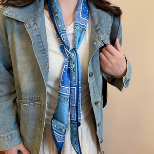 Detail of blue paisley print silk scarf necklace paired with a vintage denim jacket