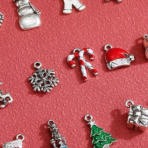 Christmas themed alloy charms featuring snowflakes and trees on a festive red background