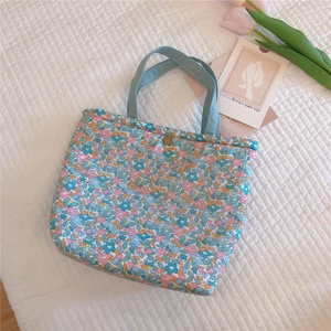 Close-up of floral cotton tote bag featuring vintage metal snap button and soft fabric handles