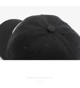 Close-up of the crown stitching and top button on a black washed cotton baseball cap