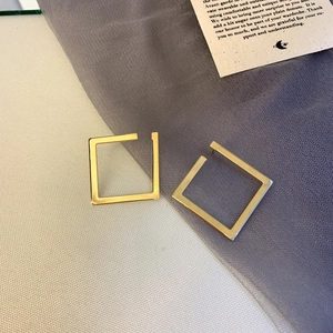 Macro view of geometric square gold earrings with a fine brushed metallic finish