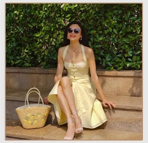 Straw tote bag with lemon embroidery paired with a yellow dress in a resort setting