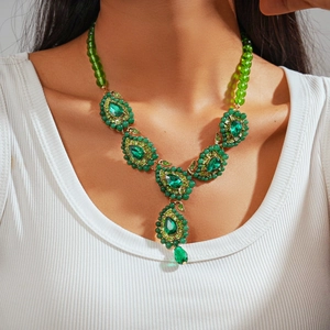 Dettaglio della collana con cristallo a goccia verde smeraldo e montatura dorata