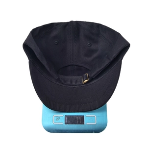 Black short brim cotton baseball cap weighing 77g on a blue scale for outdoor sports