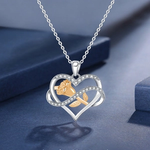 Detail of silver heart necklace with gold rose inlay and crystals on blue velvet background