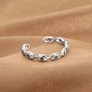 Adjustable silver Evil Eye ring with blue stones on a premium silk texture background