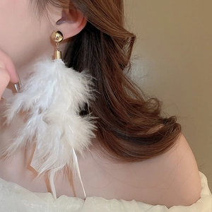Close-up of elegant long white feather tassel earrings worn by a model for a luxury look