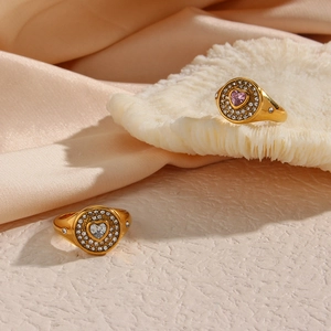 Close-up of gold stainless steel rings with heart-shaped zircon on champagne silk