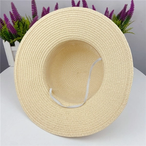 Detailed view of wide brim straw sun hat with woven texture and white elastic wind rope