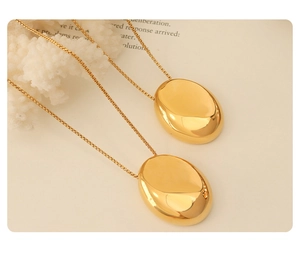 Close-up of gold oval pendants with a smooth mirror finish on an elegant coral backdrop