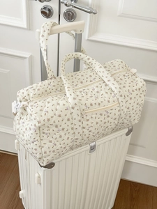 Dettaglio della borsa da viaggio trapuntata a fiori su una valigia bianca