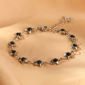 Detailed macro view of silver star bracelet with black zircon inlay on silk fabric