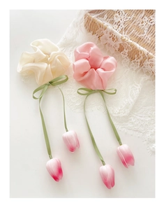 Detail of silk hair ties with pink tulip charms and green ribbon bows in soft white and pink
