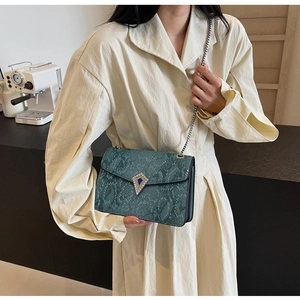 Detail view of emerald green snake pattern crossbody bag with silver chain and metal buckle