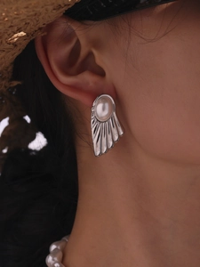 Macro shot of silver shell fan earrings with pearl inlay and vintage ribbed texture