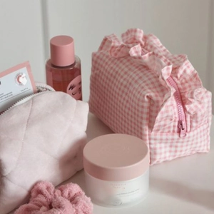 Detail shot of pink quilted velvet and ruffled plaid cosmetic bags with skincare bottles