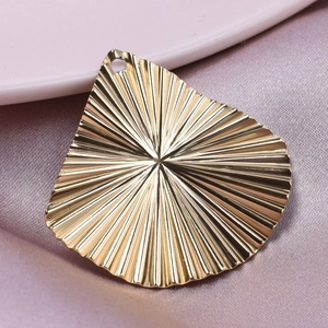 Macro view of gold stainless steel fan-shaped pendant with textured radial pattern detail