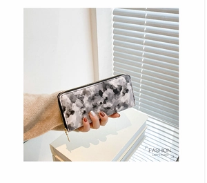 Close-up of long marble pattern wallet with a metal zipper held by a hand