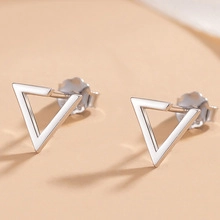 Dettaglio macro di orecchini a triangolo in argento con finitura metallica e chiusure