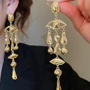 Detailed macro view of gold-tone long drop earrings with hammered vintage metal texture