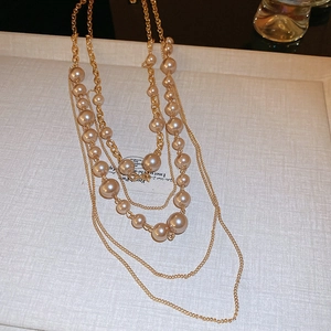 Detailed view of layered faux pearl necklace with gold-tone chain on a tray