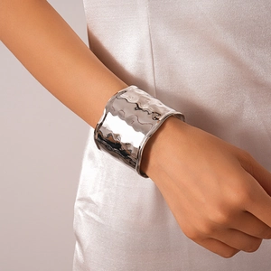 Detailed view of wide silver-toned cuff bracelet featuring unique hammered texture on wrist