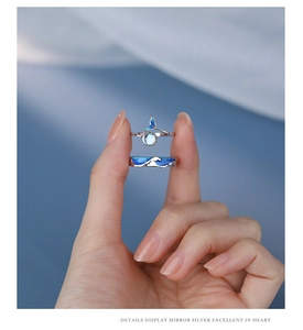 Detailed macro view of silver whale tail and blue ocean wave enamel couple rings