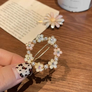 Detail of floral hair clip set with rhinestones and pearls on a warm wooden table