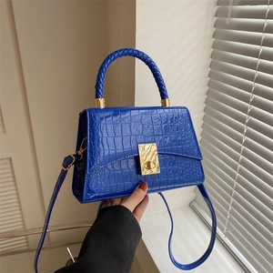 Cobalt blue crocodile pattern handbag with woven handle and gold twist lock in hand