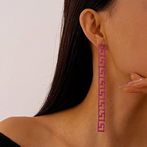 Detail shot of long tassel earrings with pink rhinestones and Greek key patterns on model
