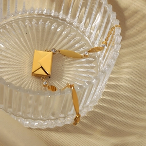 18k gold plated stainless steel envelope bracelet with cubic zirconia in a glass tray