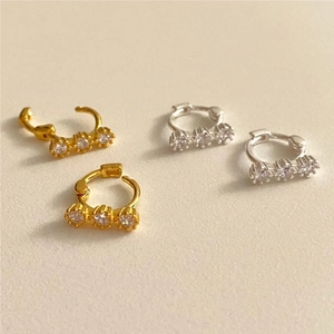 Close-up of minimalist 925 silver hoop earrings with three zircon stones in gold and silver