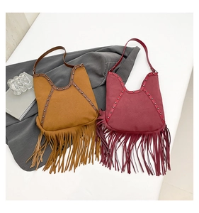 Detail shot of bohemian fringe bag with metallic studs and sun face embossed pattern