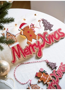 Close-up of wooden Merry Xmas gingerbread man ornaments with festive pine and lights decor