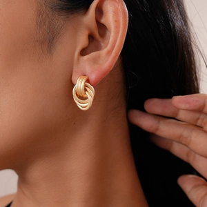 Close-up of stylish gold multilayer geometric hoop earrings worn by a female model