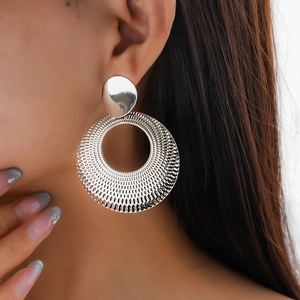 Macro shot of silver circular earrings with radial texture on a model wearing detail