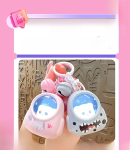 Detail of cute glowing astronaut backpack keychains in pink and grey with bells