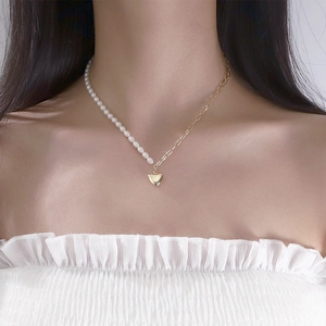 Detailed view of heart pendant necklace with half pearl and half gold chain
