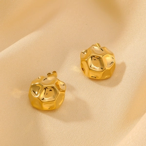 Minimalist golden hollow earrings with honeycomb texture on soft silk fabric background