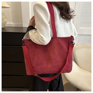 Detail of burgundy corduroy tote bag showing ribbed texture and versatile crossbody strap