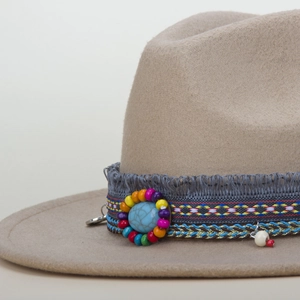 Close-up of ethnic beaded band with turquoise and fringe on beige wool jazz hat