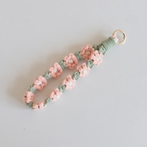 Detail of hand-woven daisy flower keychain with pink petals and gold spring ring