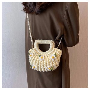 Detail of off-white woven shell bag with daisy decor and elegant pearl chain strap