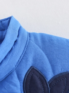 Detail of blue quilted jacket neckline showing intricate floral embroidery and stitching