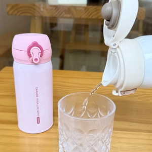 Action shot of pouring water from pink Casno stainless steel flask into a glass cup